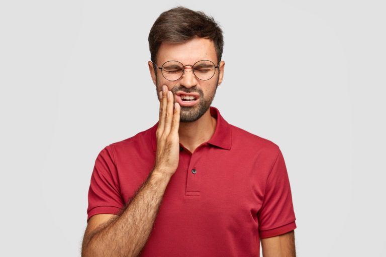 photo of caucasian man suffers painful toothache and thinking why are wisdom teeth called wisdom teeth